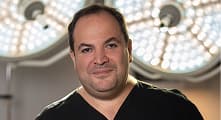 Dr. Smith in scrubs in front of surgical lights.