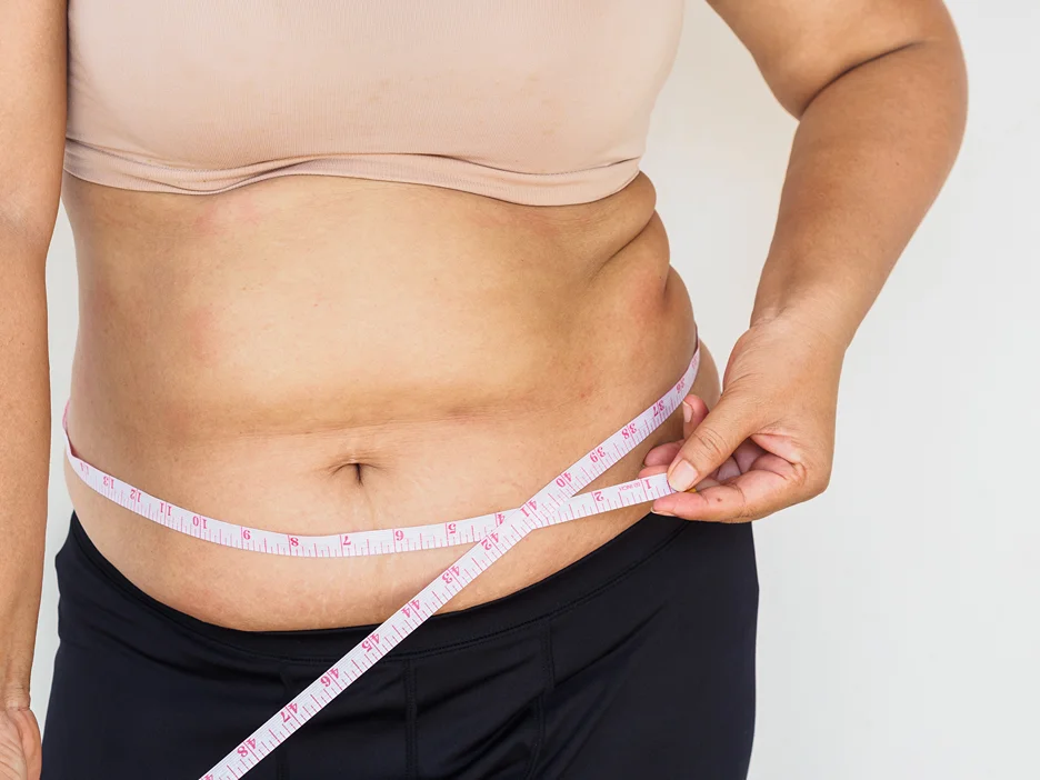 A woman measuring her fatty tummy