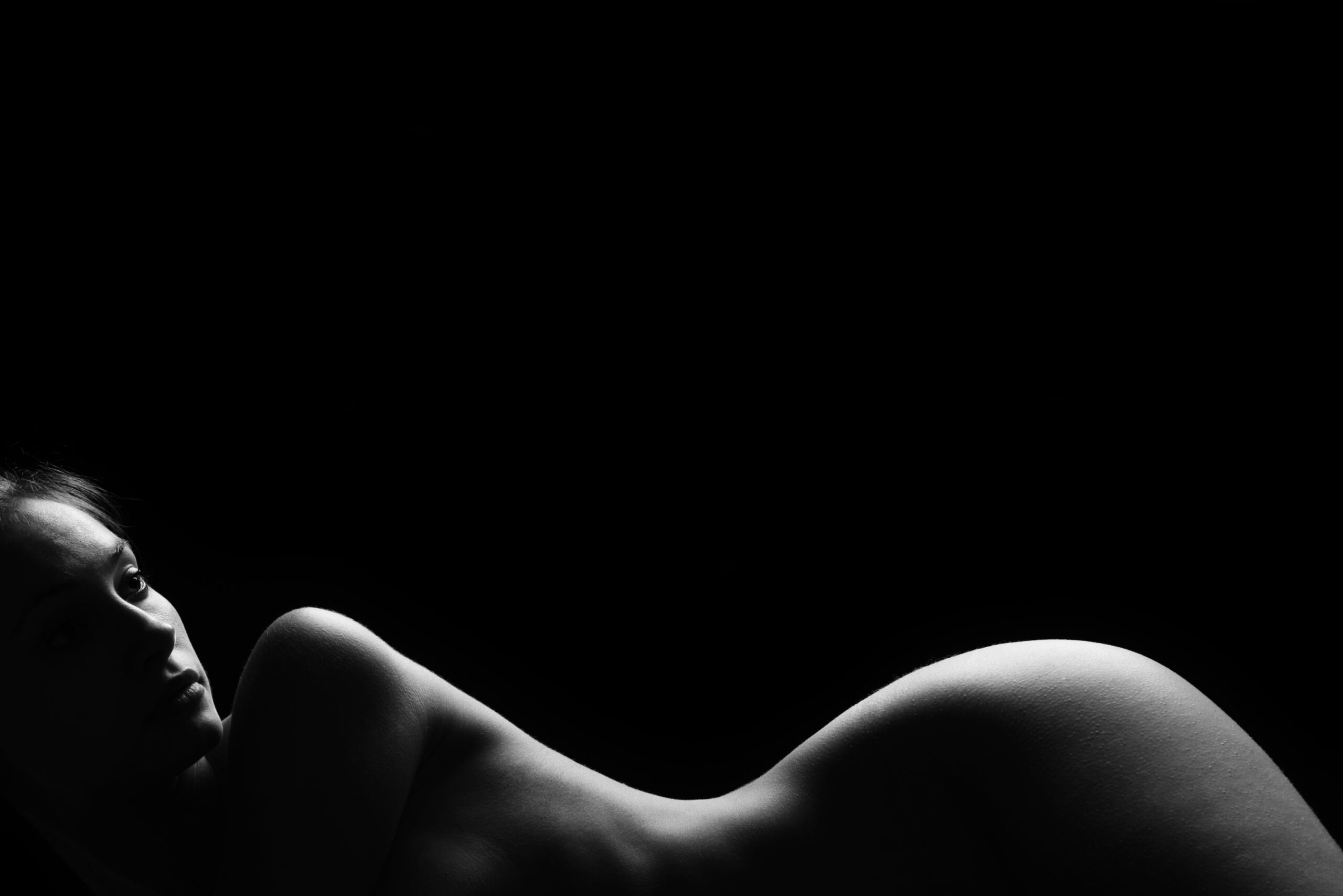 In a black and white image, a person's silhouette is illuminated against a dark background, reminiscent of the soft curve of banana rolls.